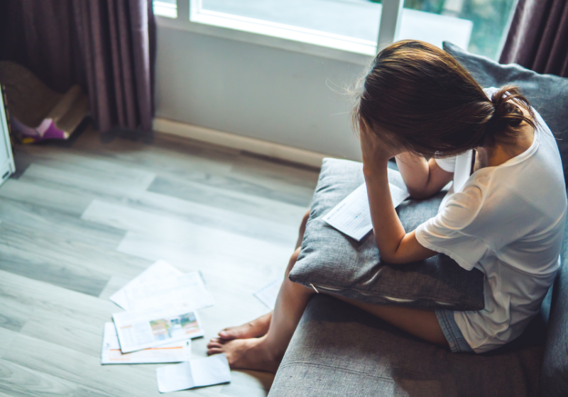 frau sitzt verzweifelt mit briefen da
